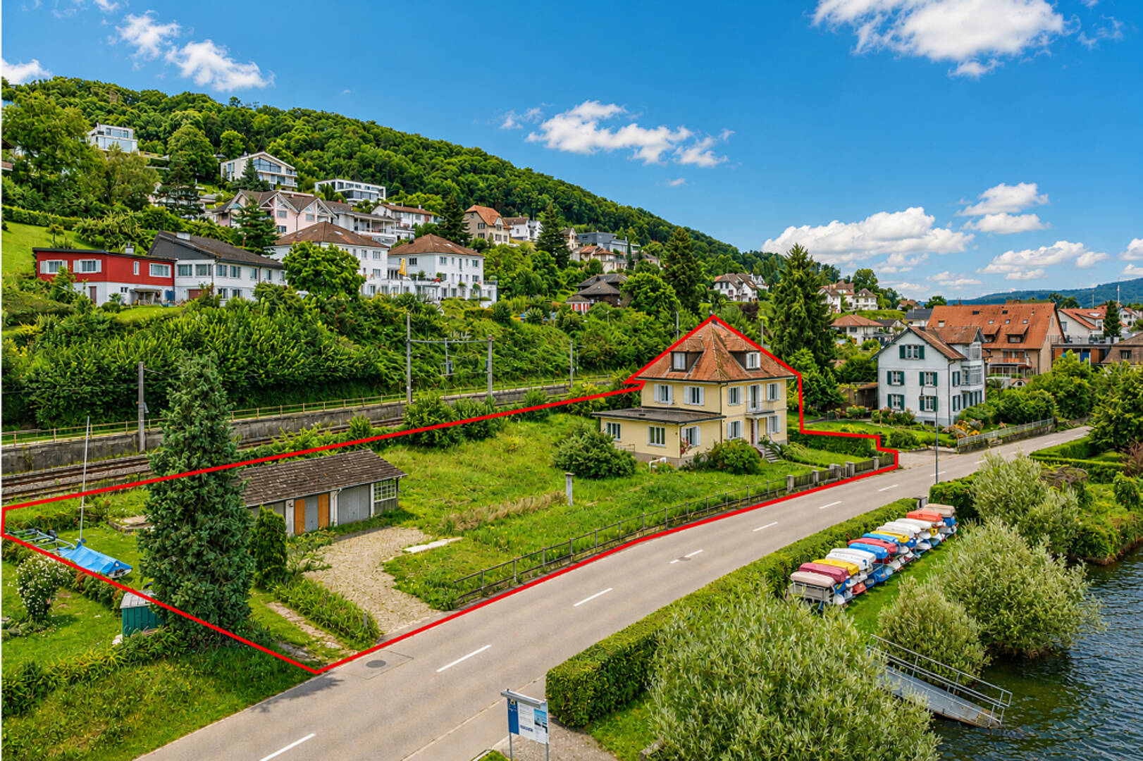 Luftaufnahme eines Grundstücks in grüner Hanglage am Wasser