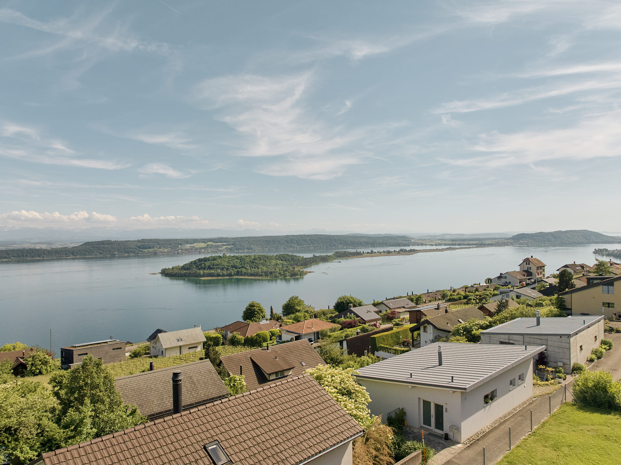 Panoramablick auf einen See mit Wohnhäusern am Hang