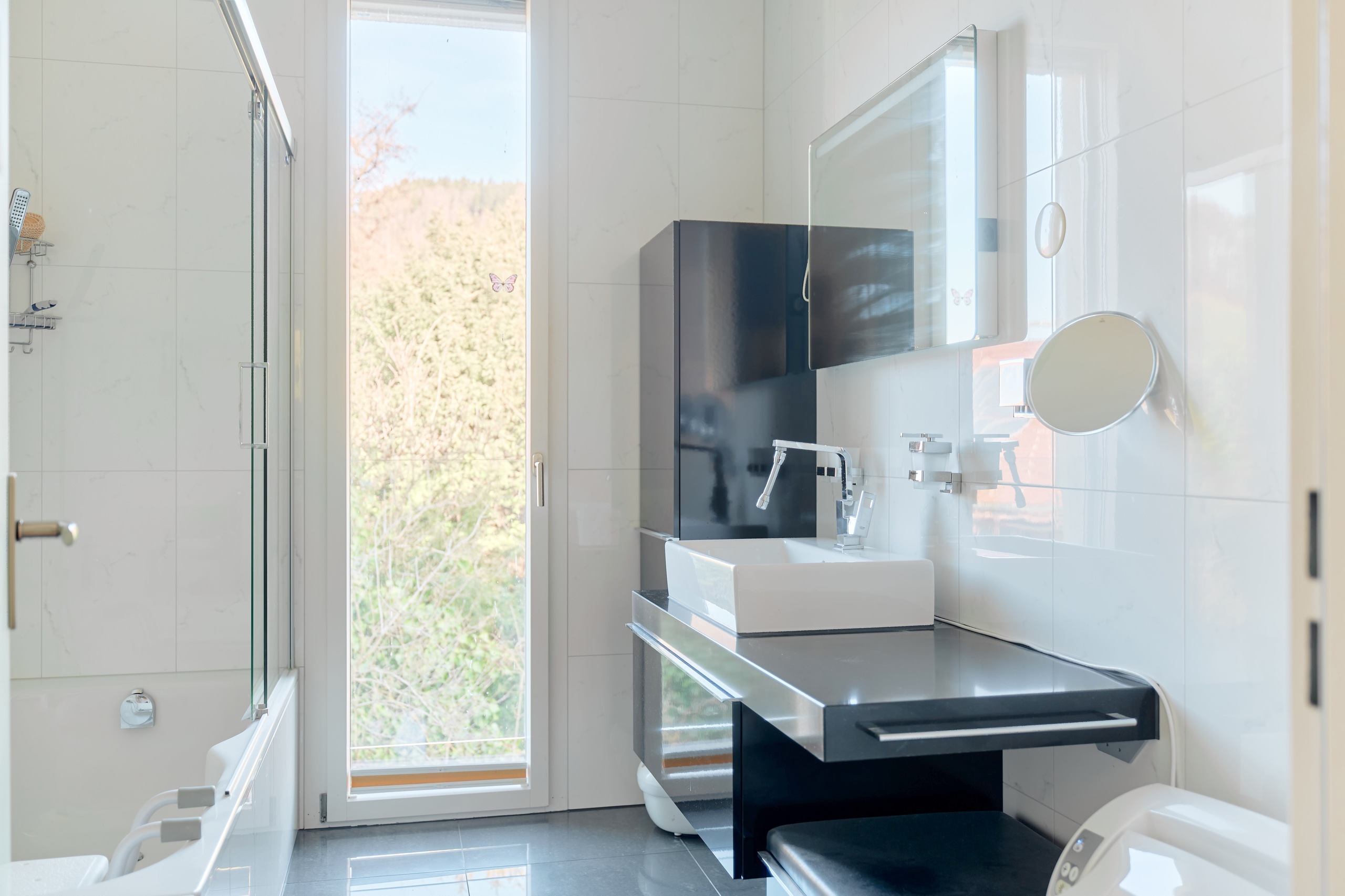 Modernes Badezimmer mit schmalem Fenster und Glasdusche