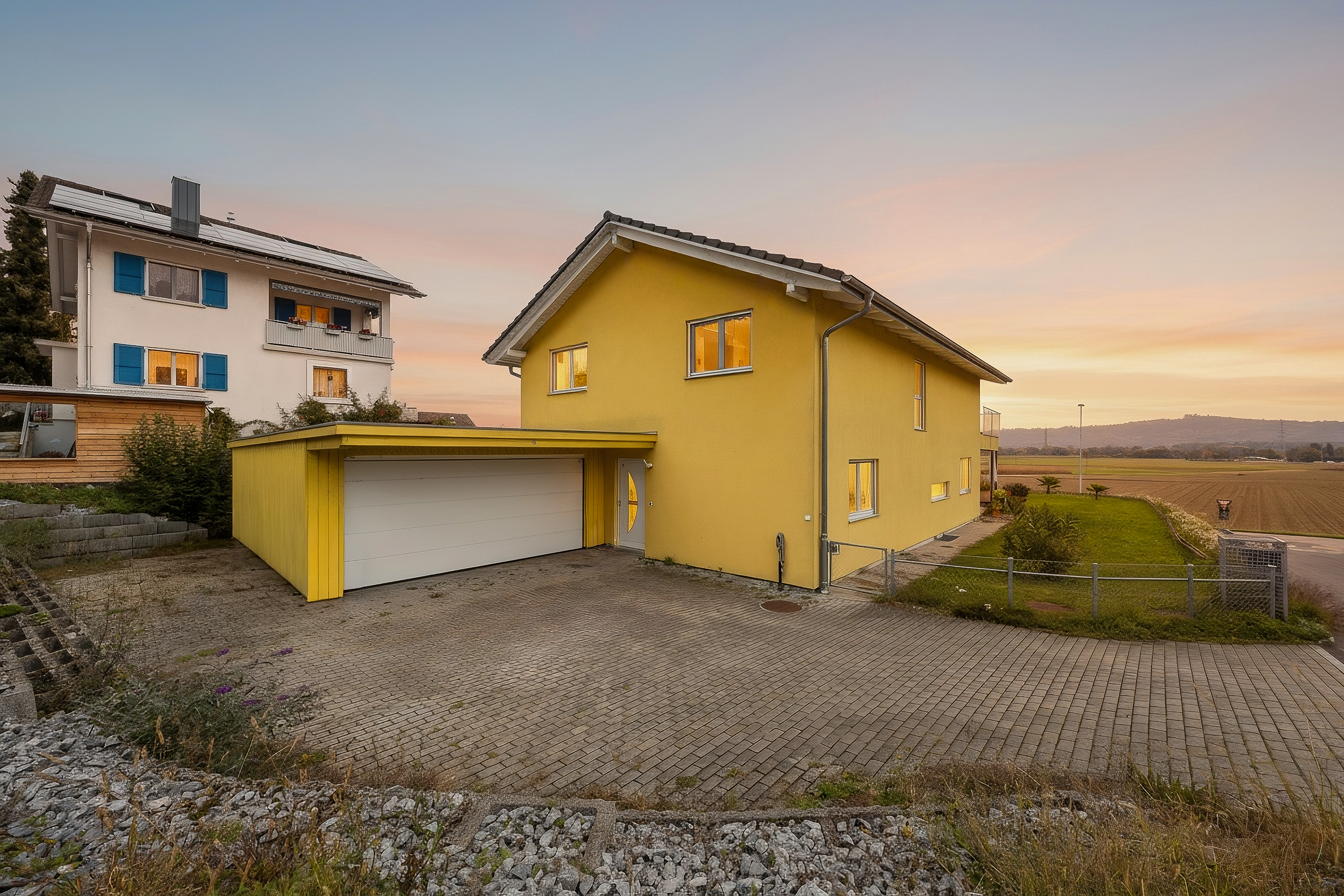 Außenansicht eines Einfamilienhauses mit Garage bei Sonnenuntergang