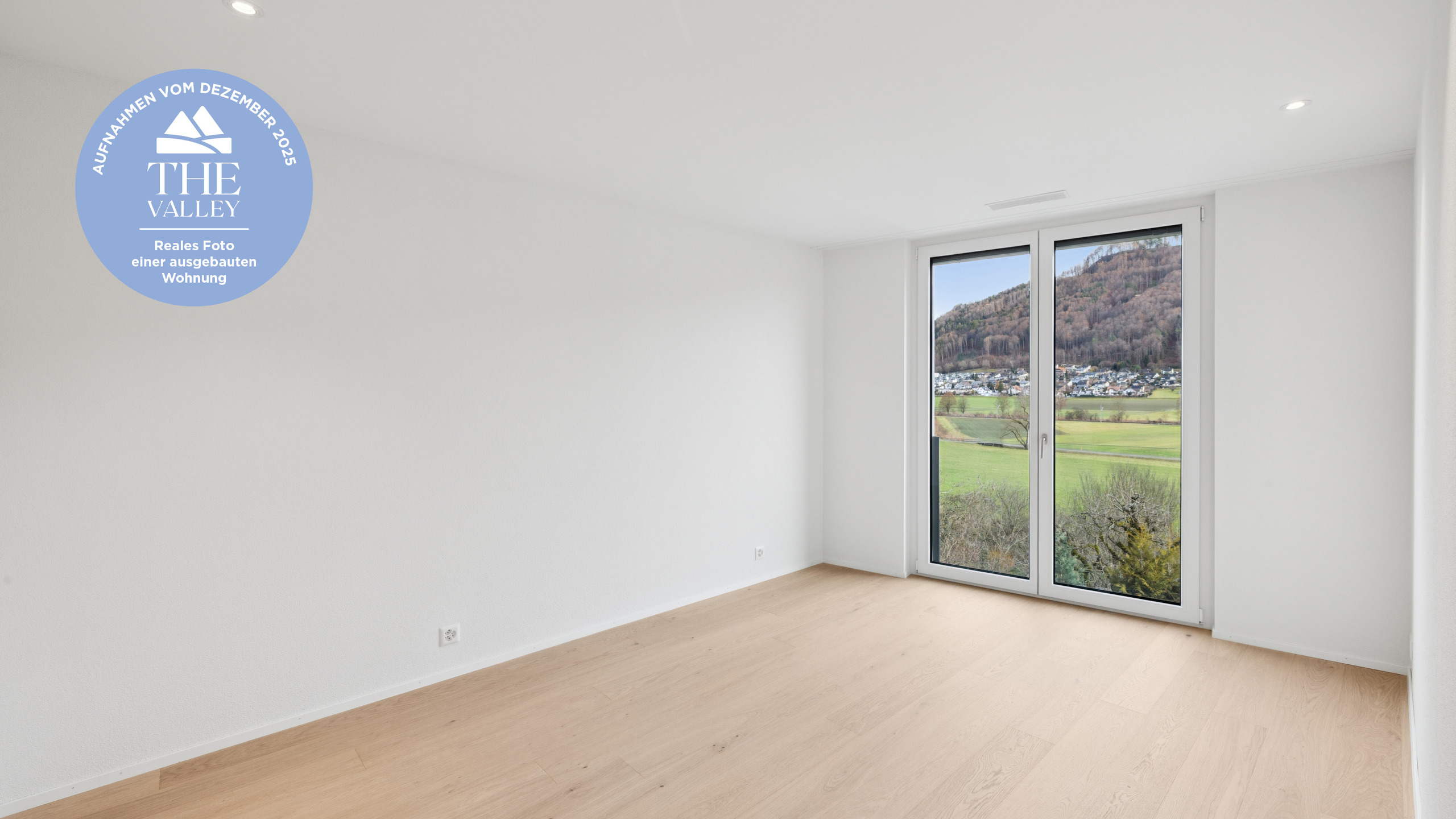 Helles, leeres Zimmer mit großem Fenster und Bergblick