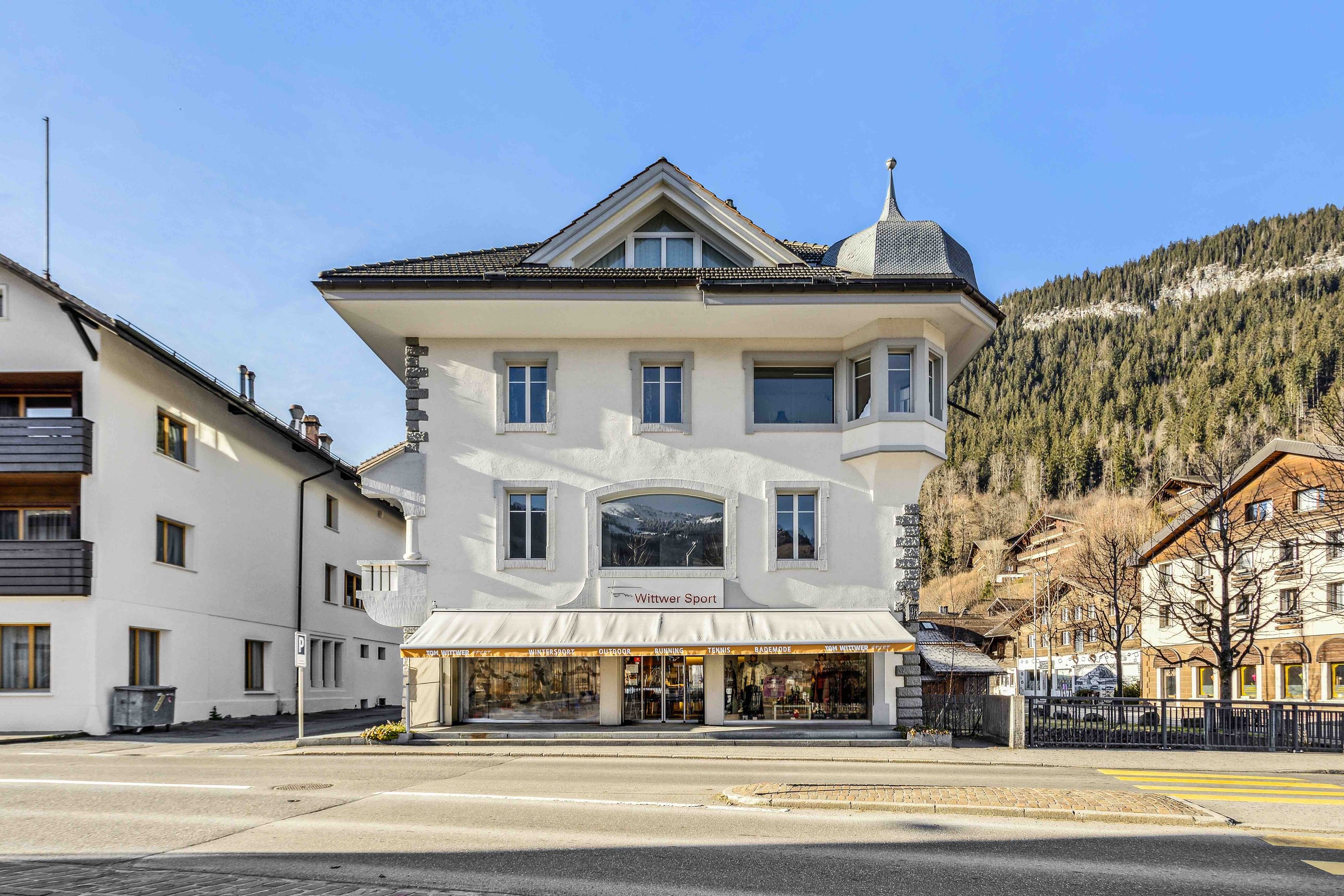 Straßenansicht eines alpinen Gebäudes mit Ladenlokal