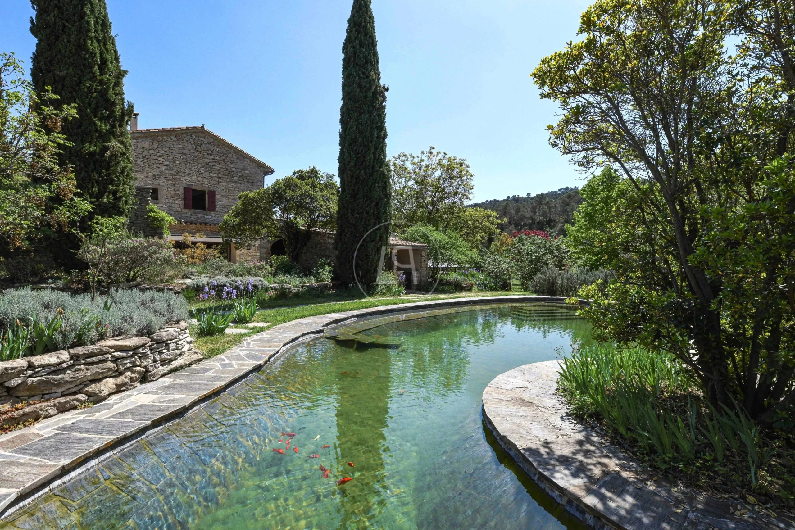 Mediterraner Außenbereich mit Natursteinvilla und Teich