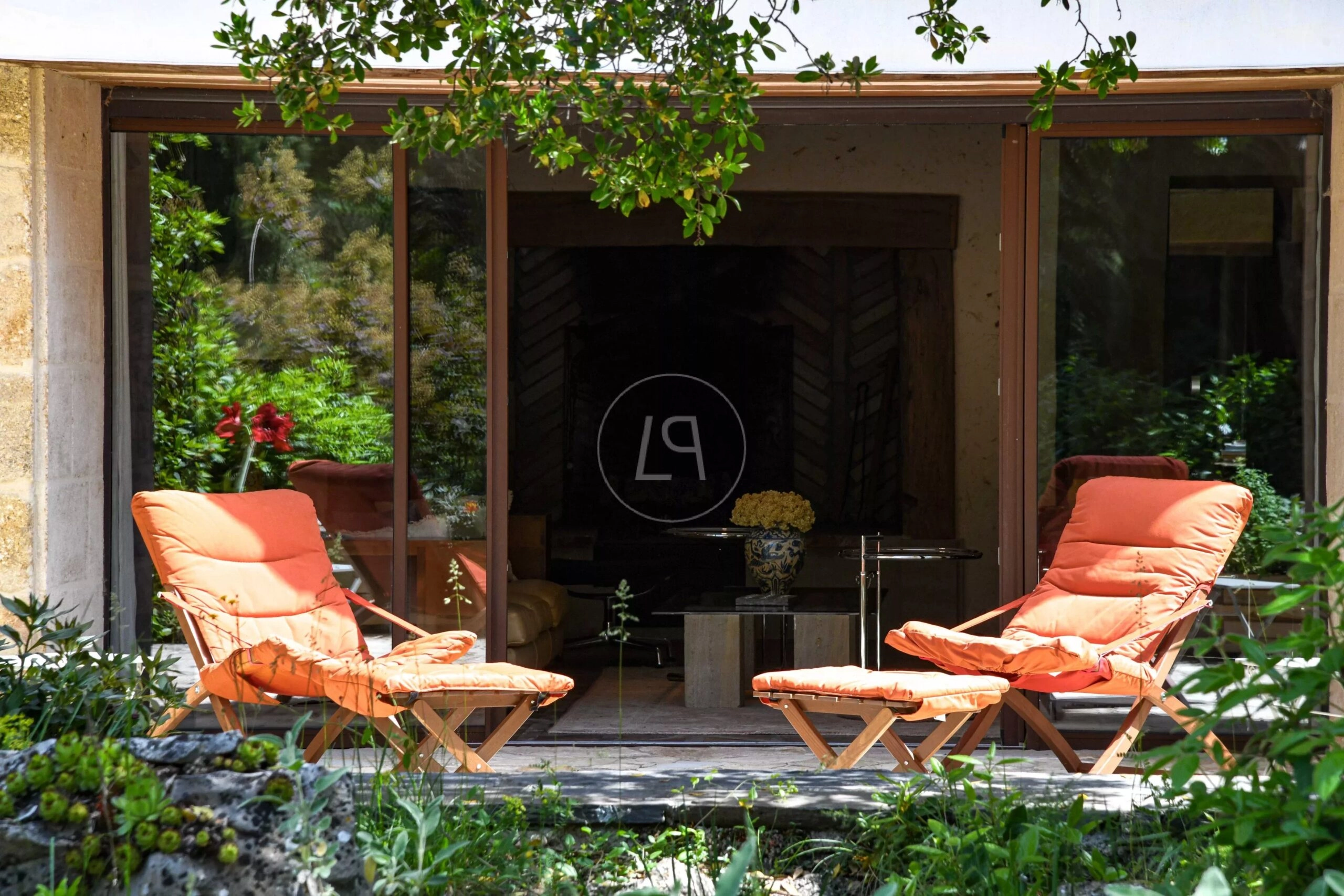 Terrasse mit Lounge-Stühlen vor großen Glasfronten