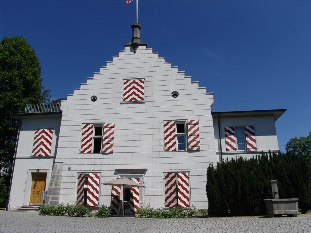 Historisches Gebäude mit markanten rot-weißen Fensterläden