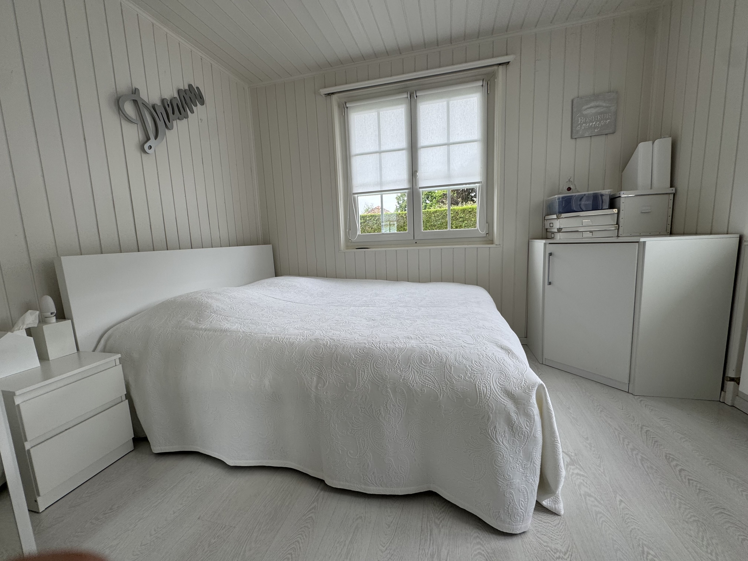Helles, schlichtes Schlafzimmer mit weißer Holztäfelung