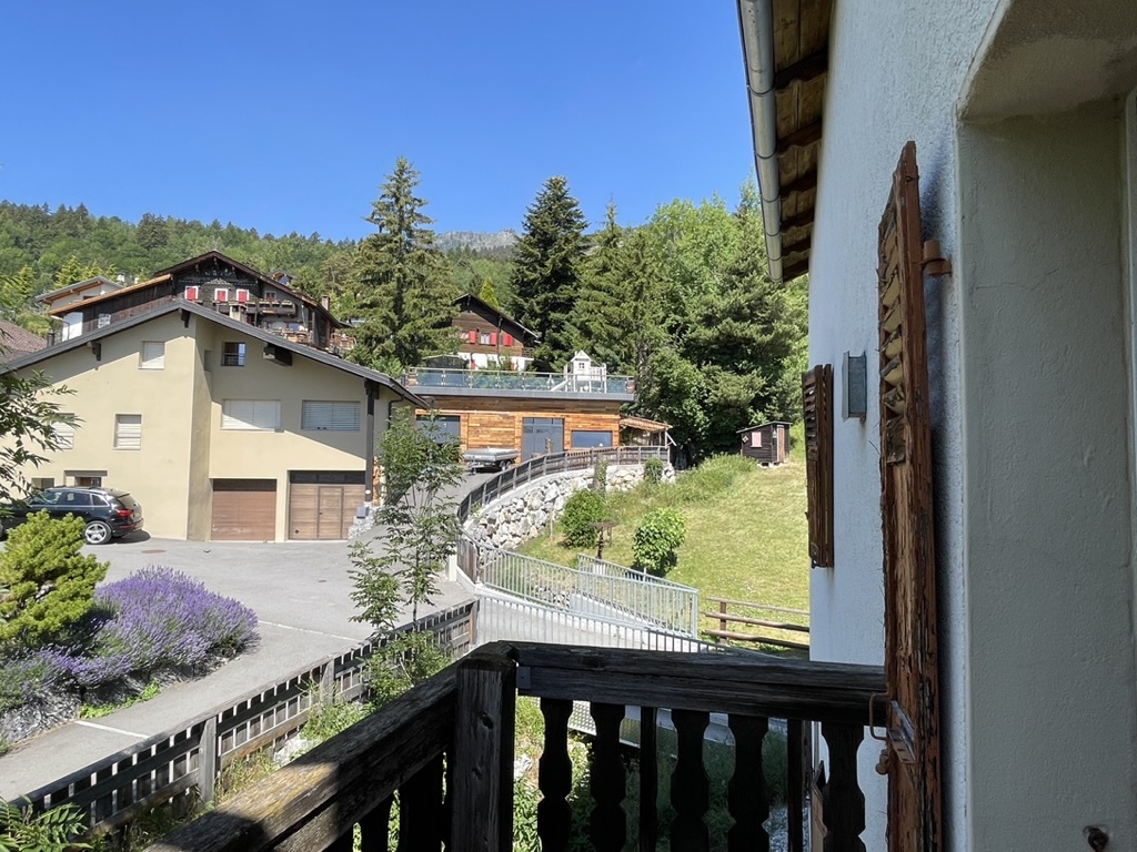 Blick vom Balkon auf alpine Wohnhäuser und Hanglage
