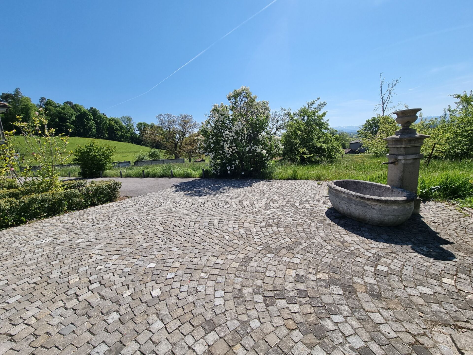 Steinpflaster-Terrasse mit Brunnen im Grünen