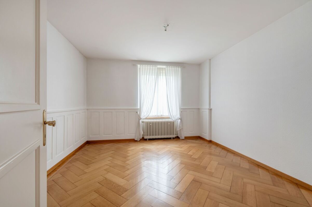 Heller leerer Raum mit Holzparkett und Fenster
