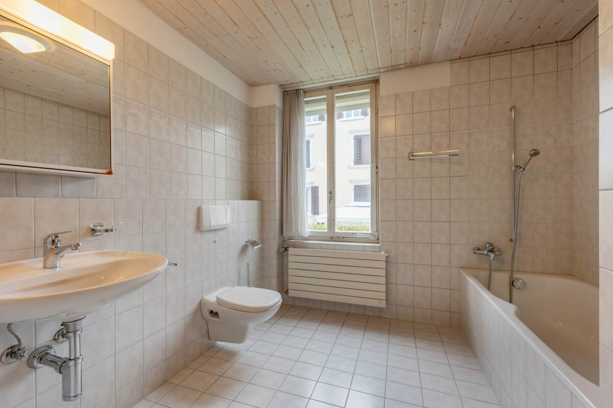 Helles Badezimmer mit Badewanne und Fenster
