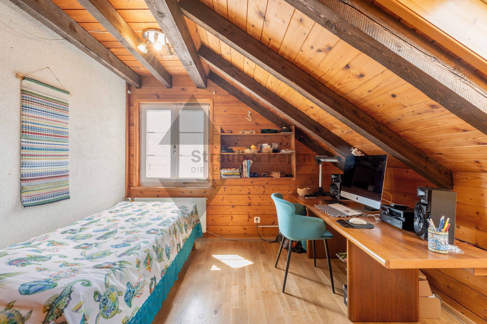 Gemütliches Dachzimmer mit Bett und Arbeitsplatz