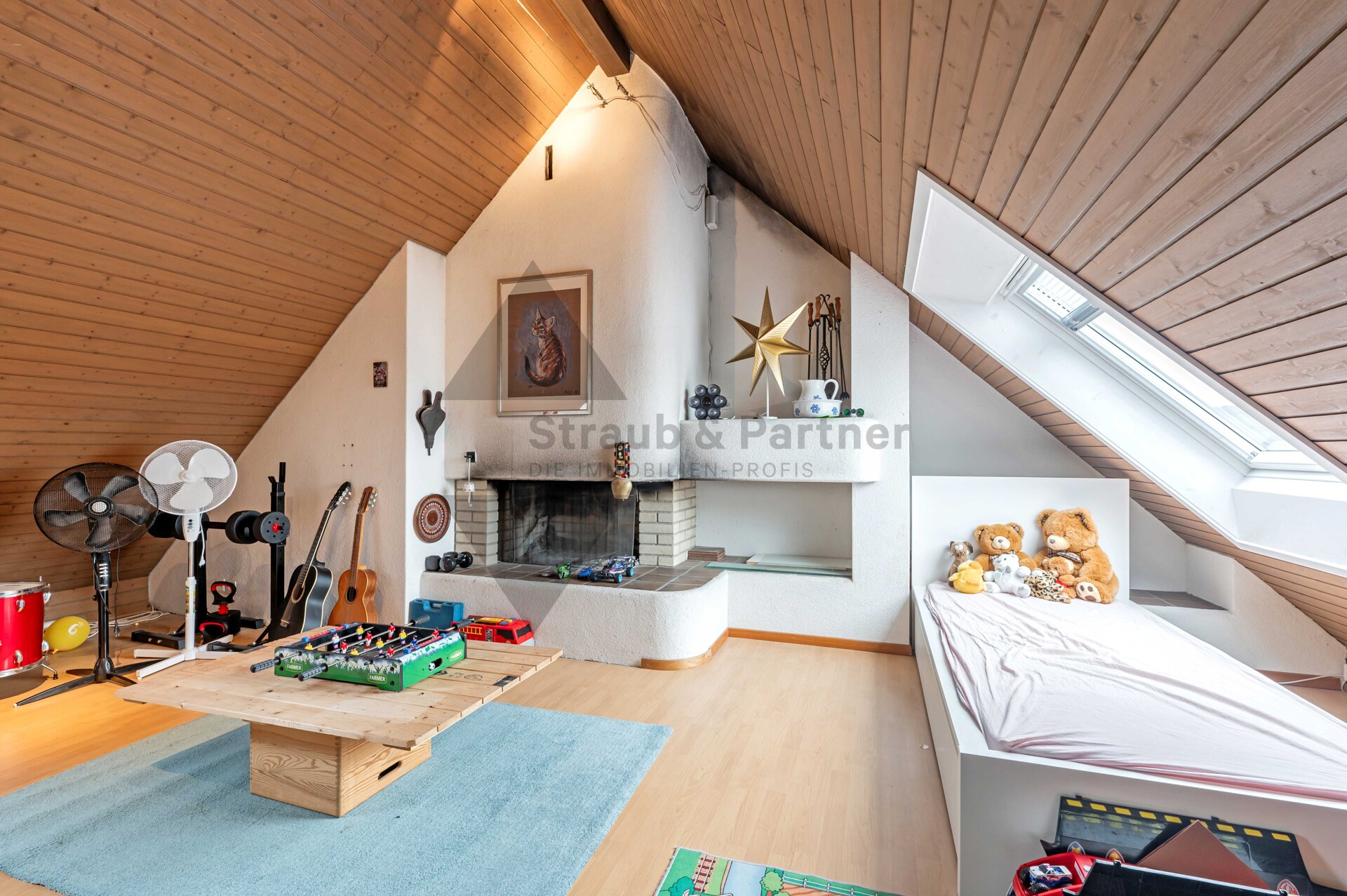 Dachgeschoss-Wohnraum mit Kamin und Spielbereich