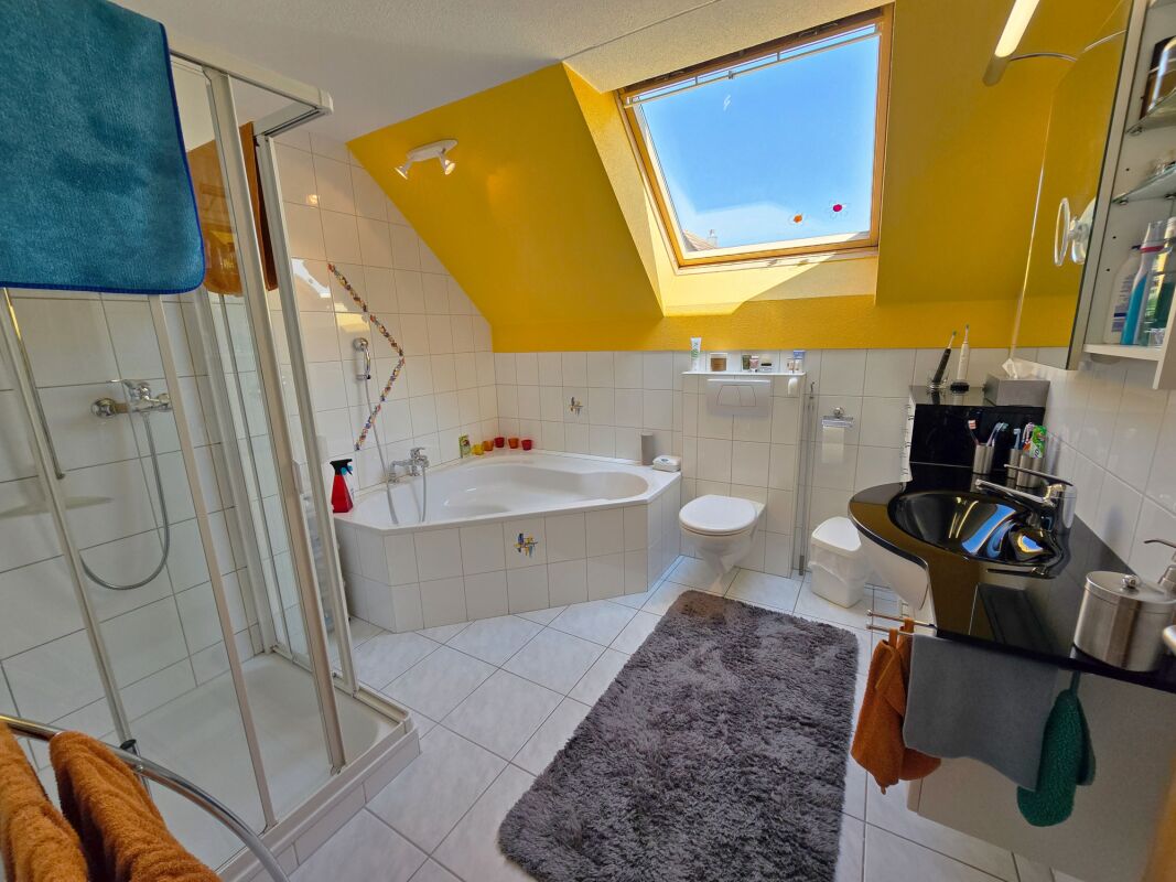 Gelbes Dachgeschoss-Badezimmer mit Badewanne und Dusche