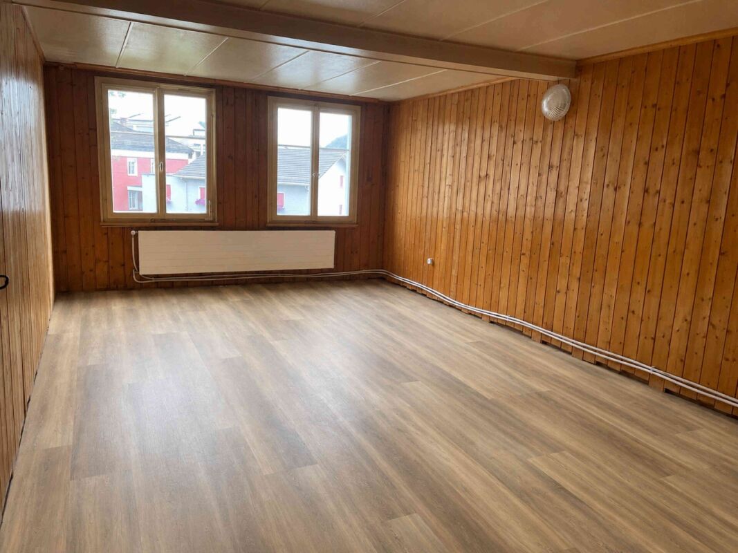Leerer Raum mit Holzvertäfelung und zwei Fenstern