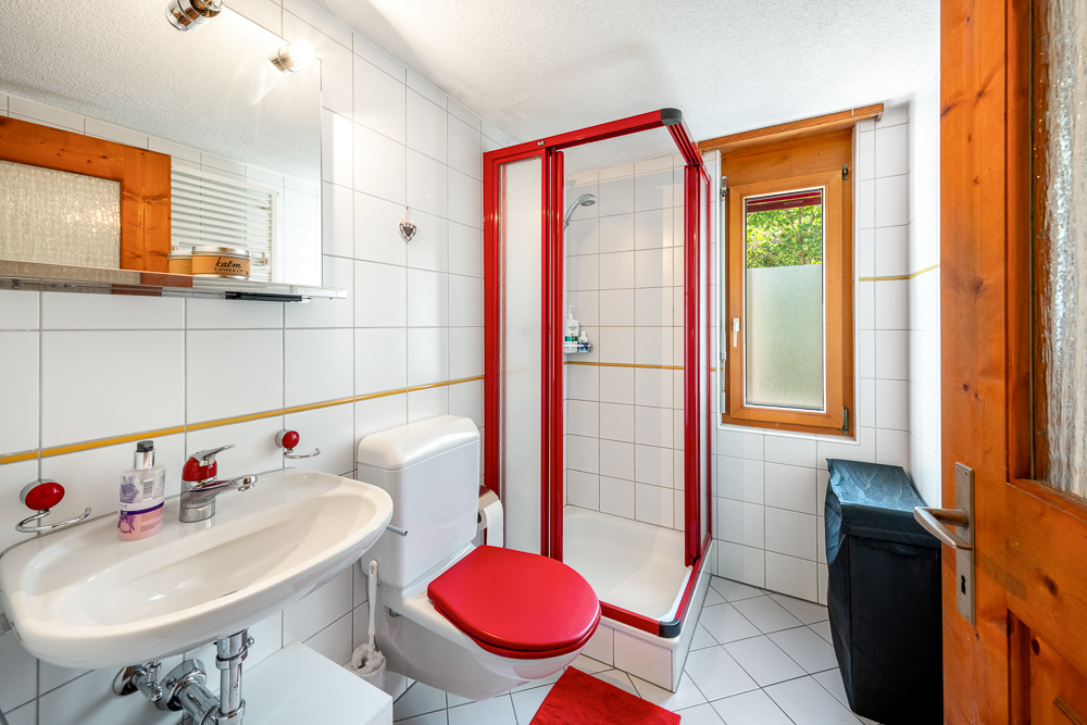 Modernes Badezimmer mit rot akzentuierter Dusche