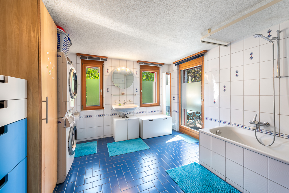 Helles Badezimmer mit Waschtisch, Badewanne und Waschmaschinen