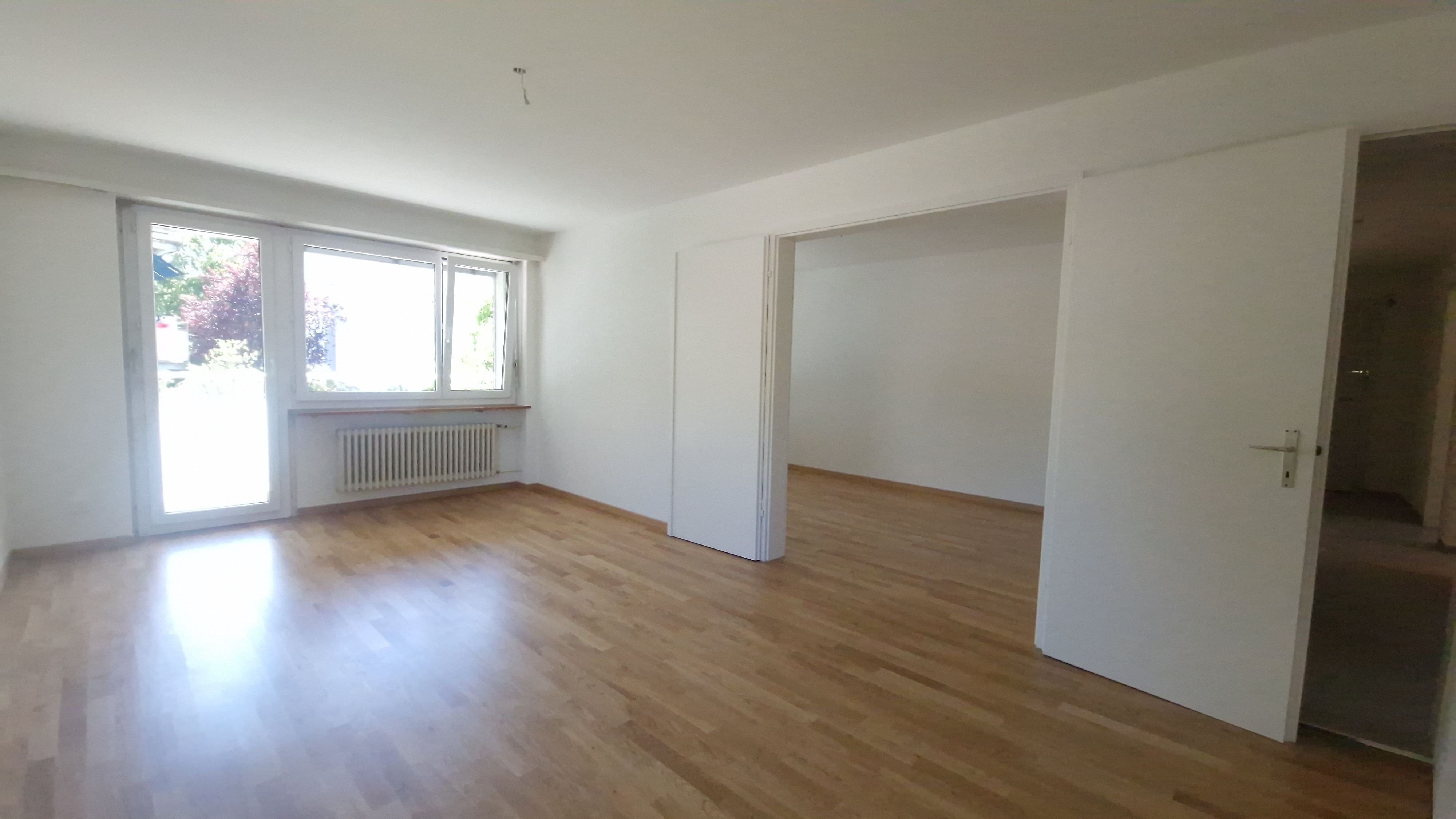 Heller, leerer Wohnraum mit Parkett und Fensterfront