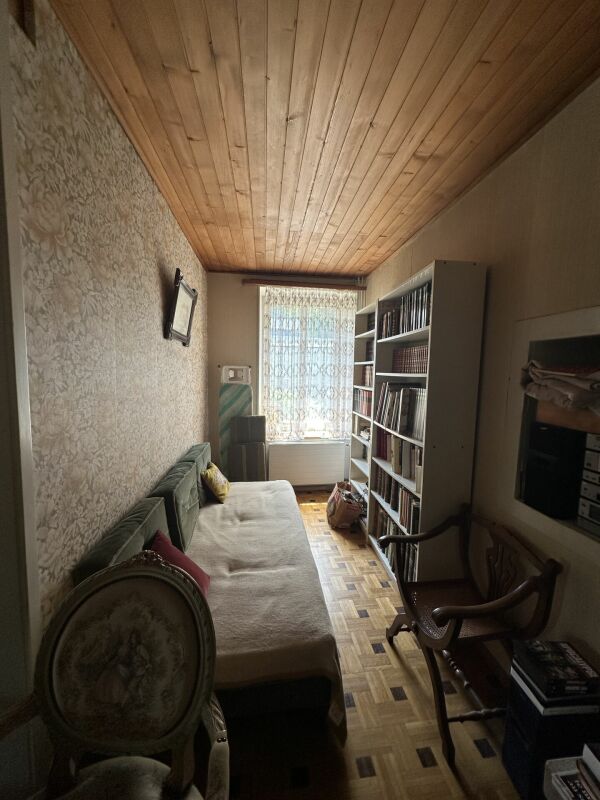 Schmaler Wohn- oder Gästezimmerbereich mit Einzelbett und Bücherregalen