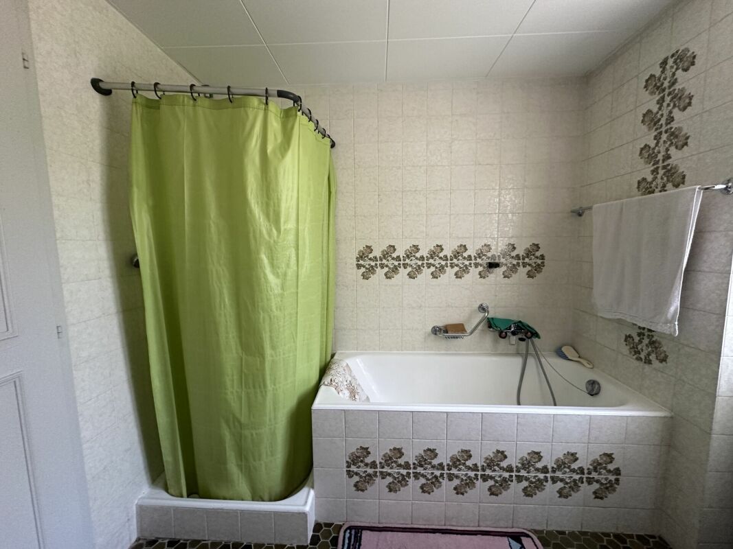 Badezimmer mit Badewanne und grüner Duschvorhang