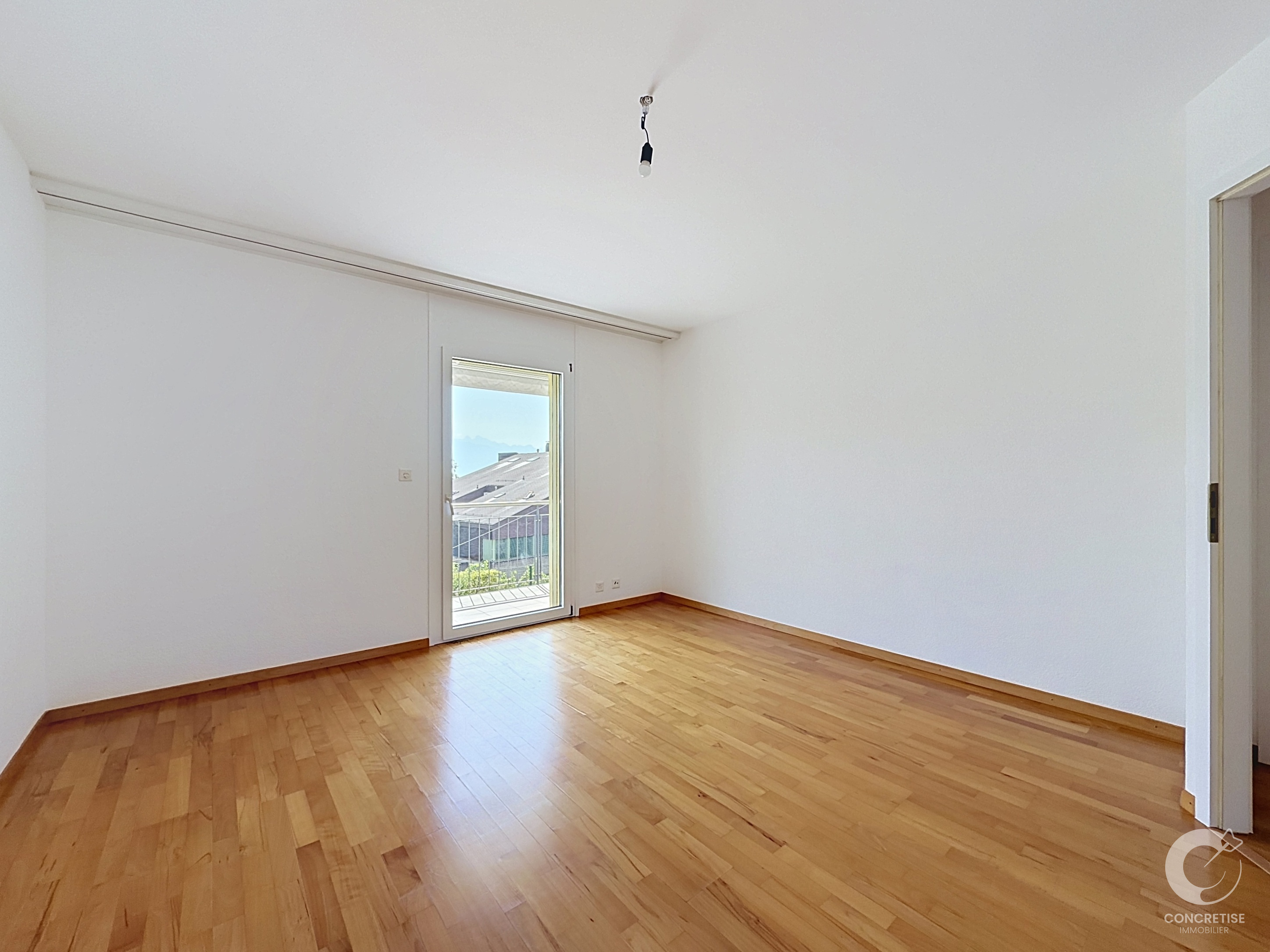 Leerer, heller Raum mit Parkett und Balkon-/Terrassentür