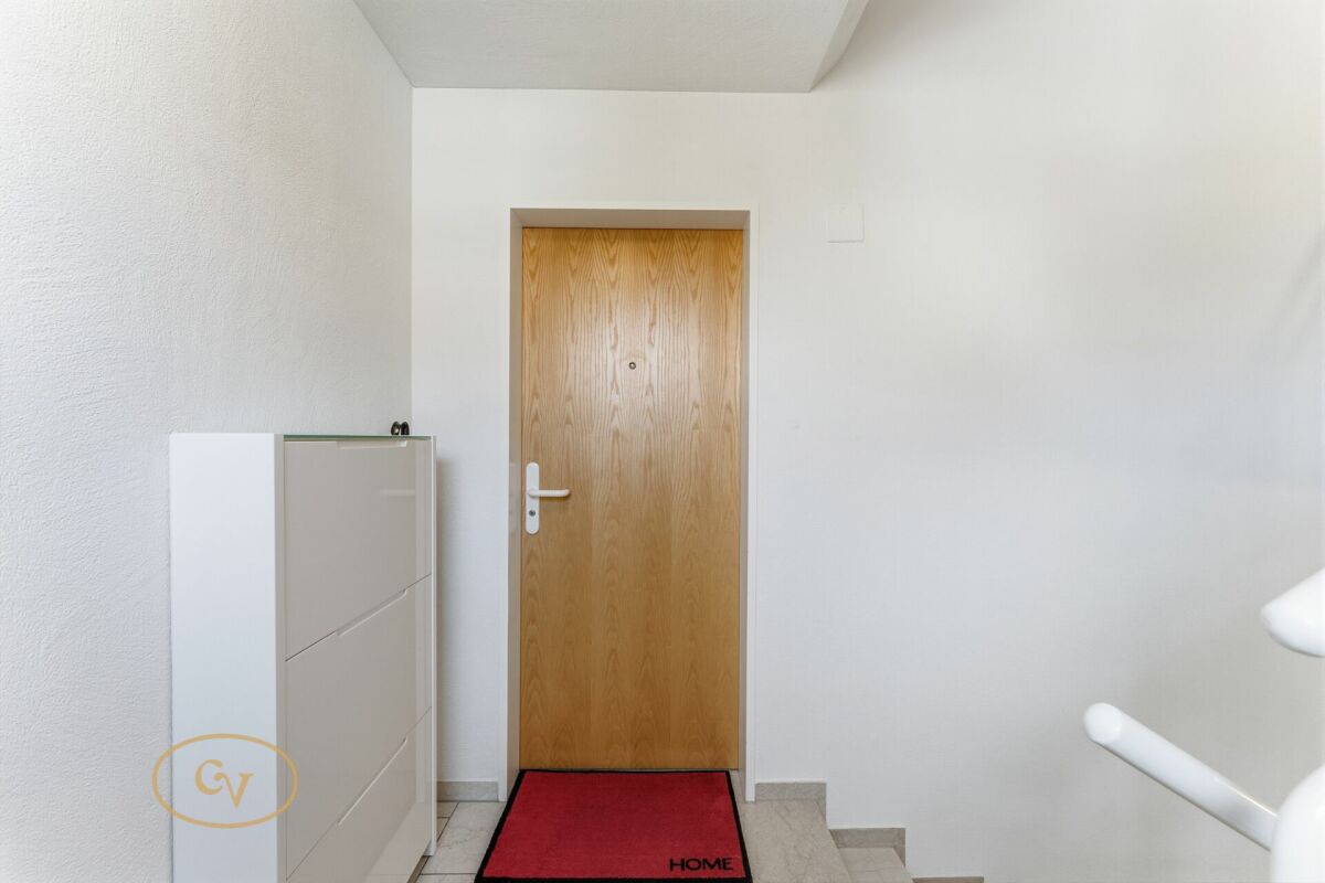 Heller Eingangsbereich mit Holztür und Schuhschrank