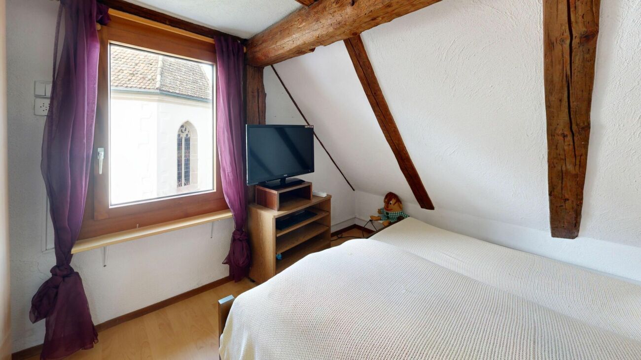 Dachgeschoss-Schlafzimmer mit sichtbaren Holzbalken