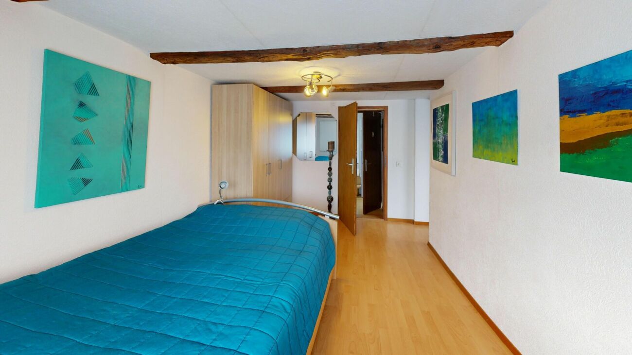 Schlafzimmer mit Holzbalken und farbiger Kunst