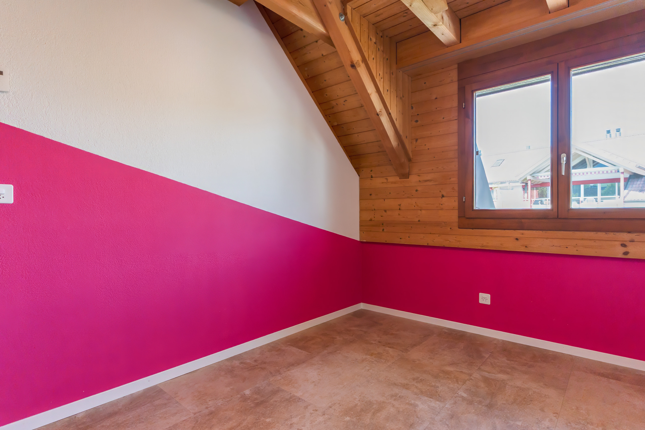 Dachgeschosszimmer mit farbiger Wand und Holzbalken