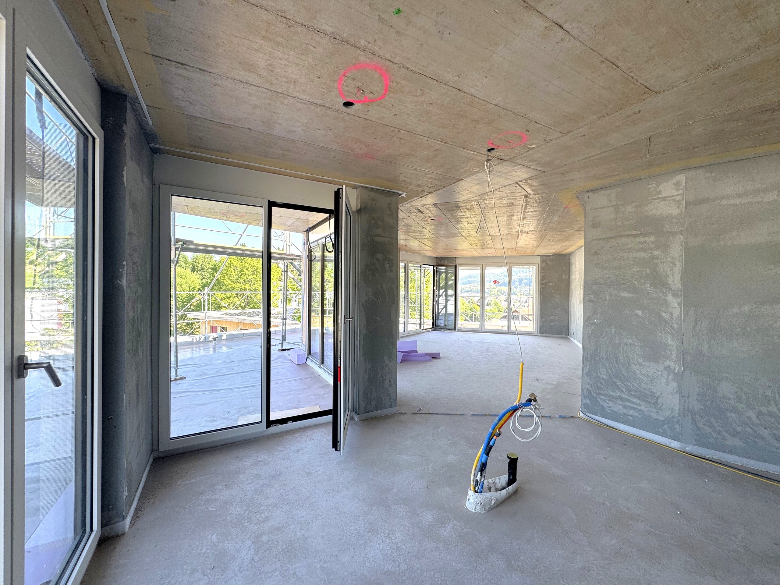 Unfertig ausgebauter Wohnraum mit großen Fensterfronten