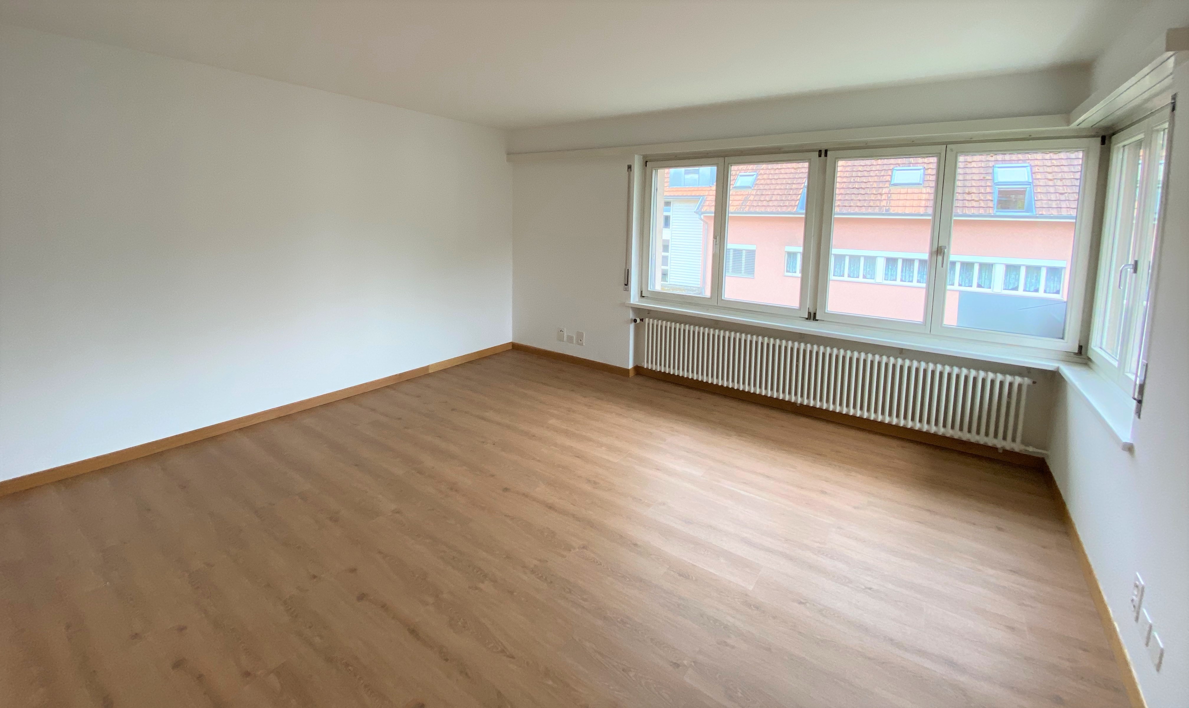 Heller leerer Wohnraum mit großen Fenstern
