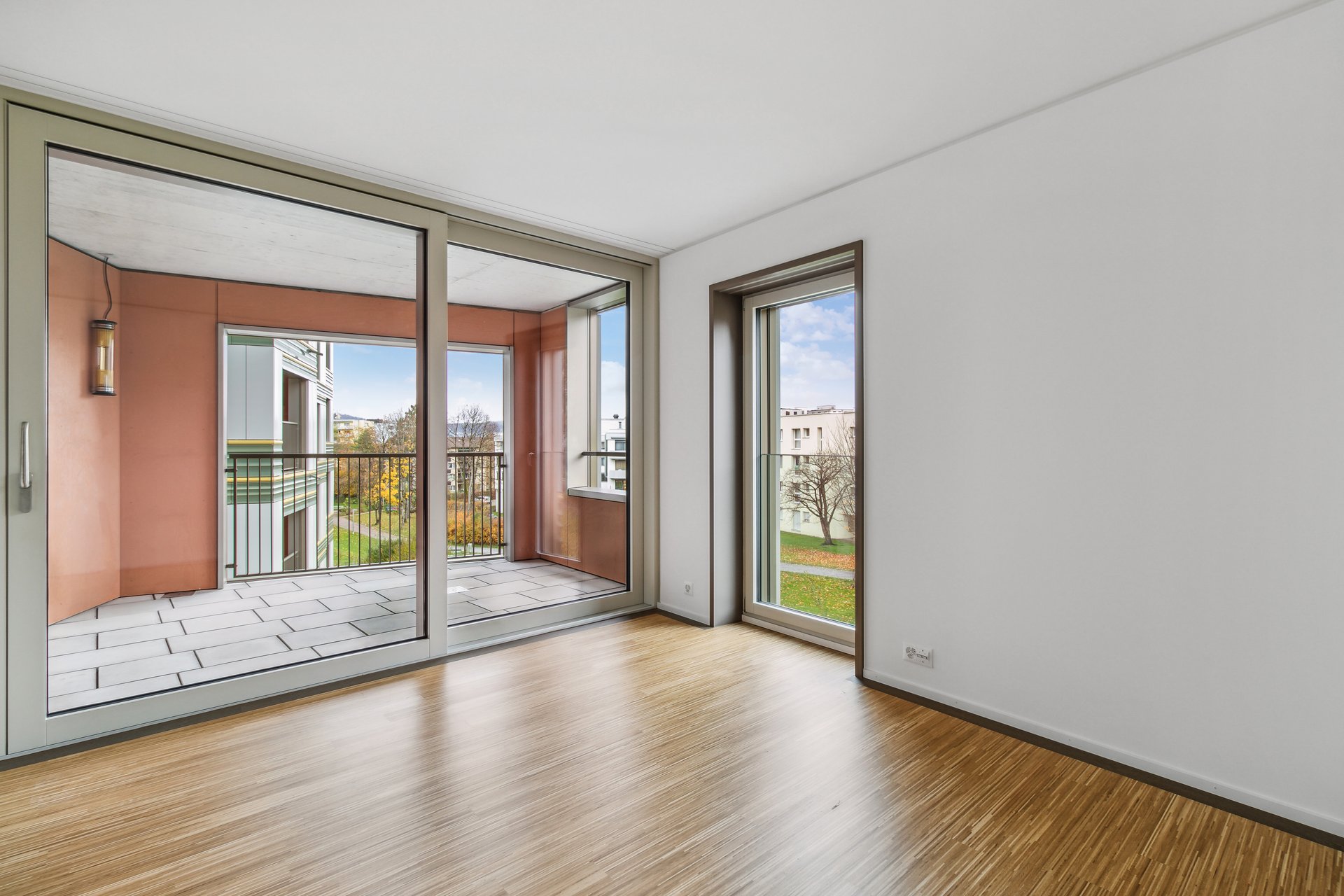 Leerer Wohnraum mit Balkon und Blick ins Grüne