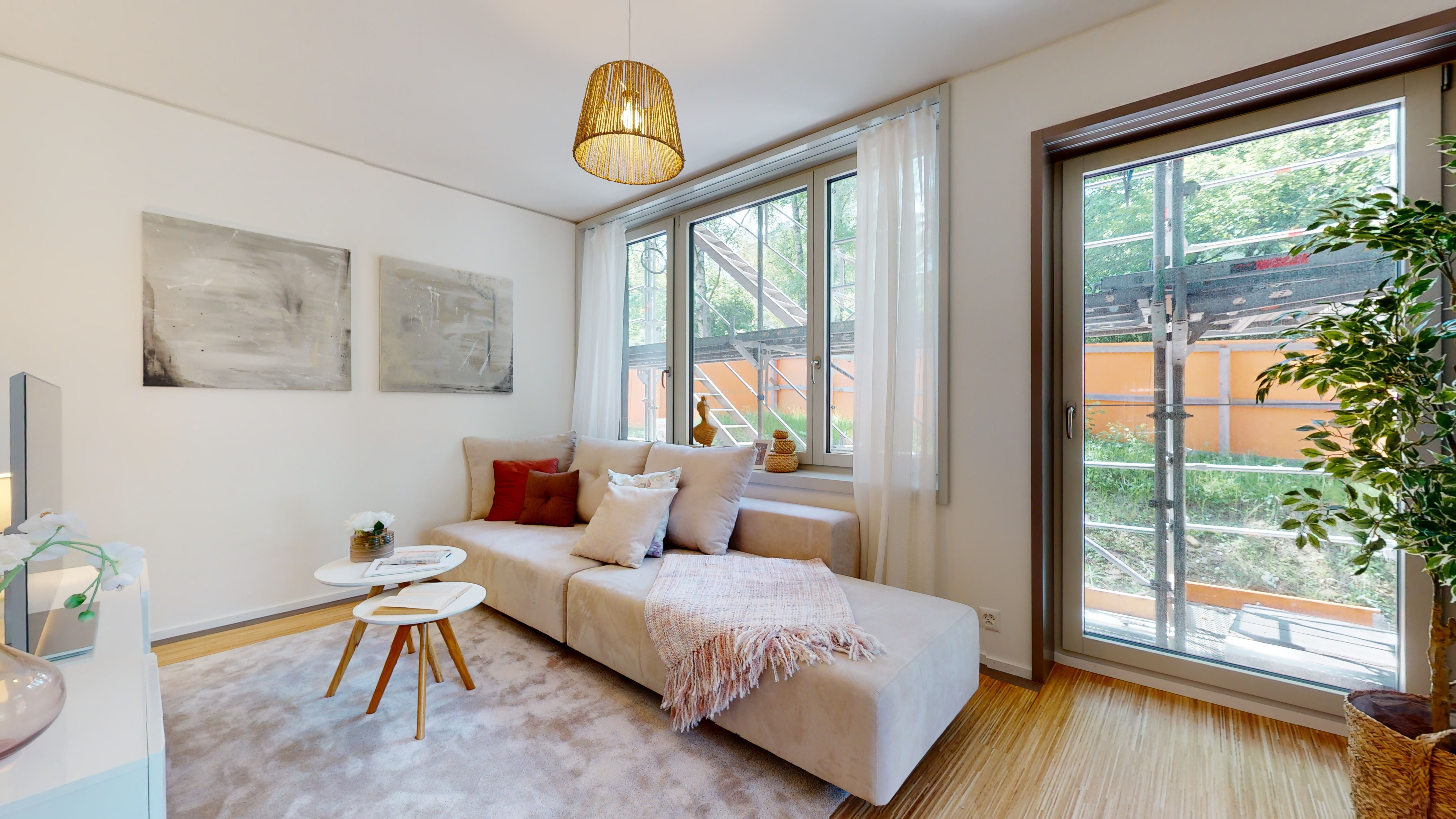 Helles Wohnzimmer mit Sofa und großen Fenstern