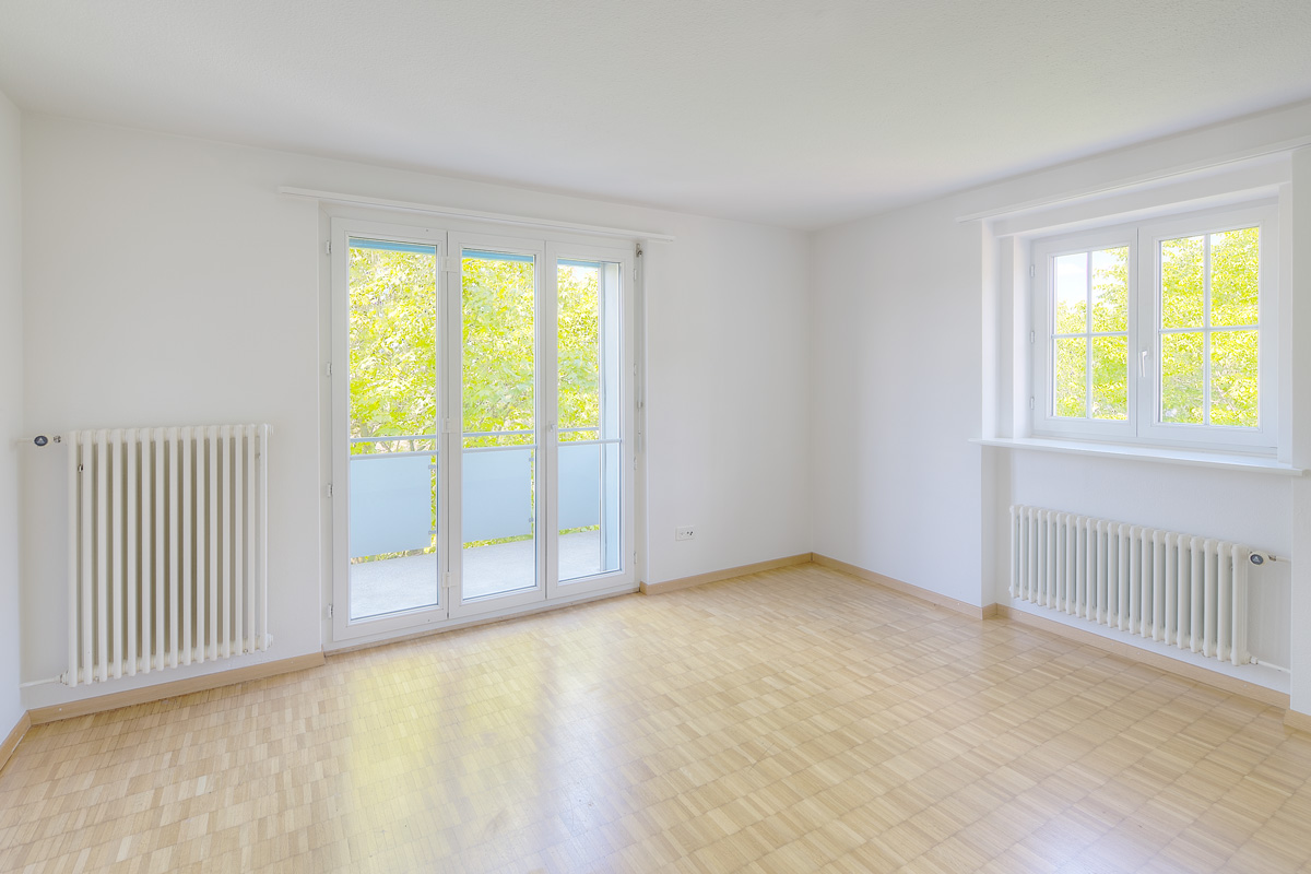 Heller leerer Wohnraum mit Balkon- und Fensterfront