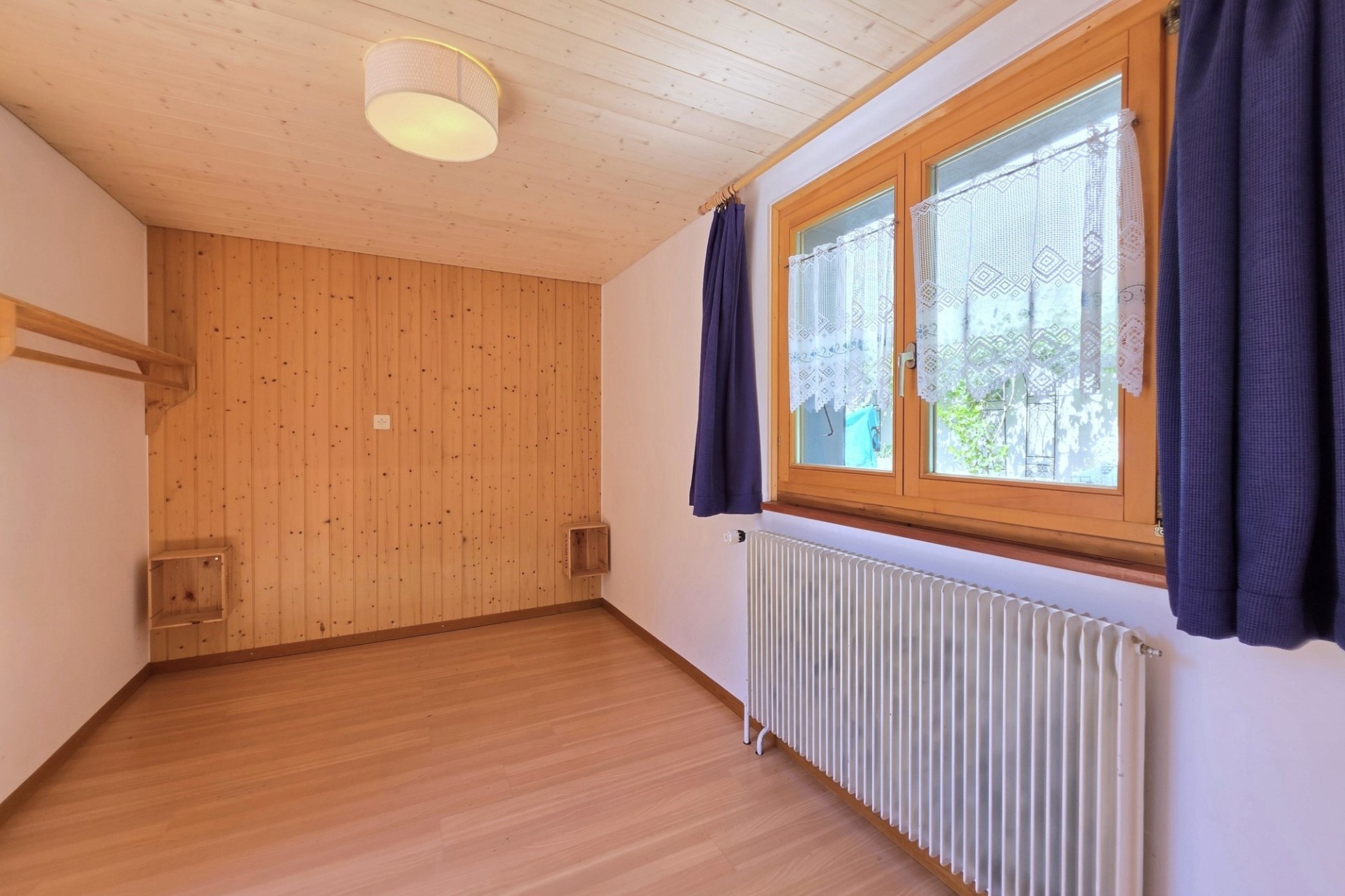 Helles, leeres Zimmer mit Holzverkleidung und Fenster