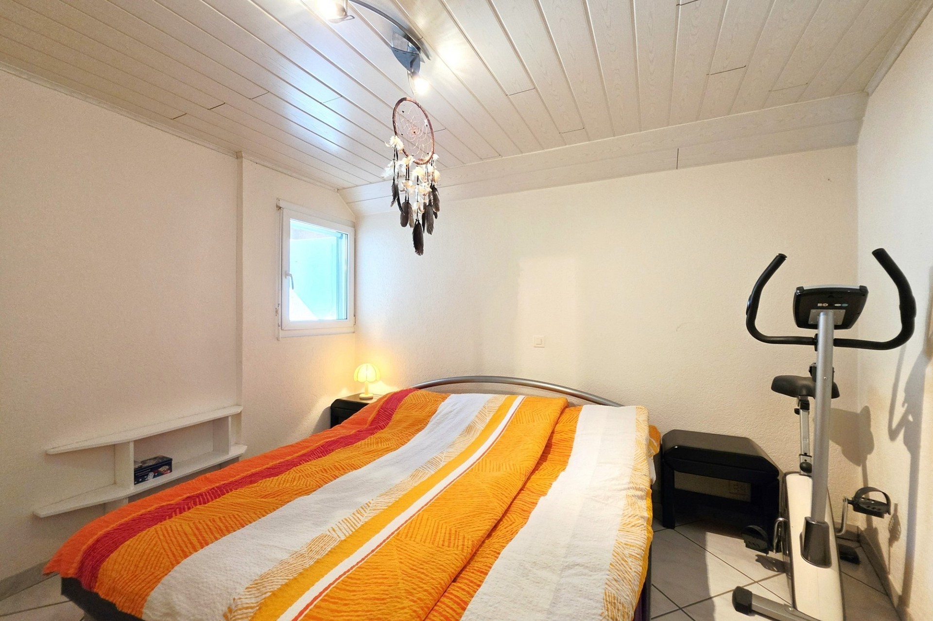 Kleines Schlafzimmer mit schräger Holzdecke
