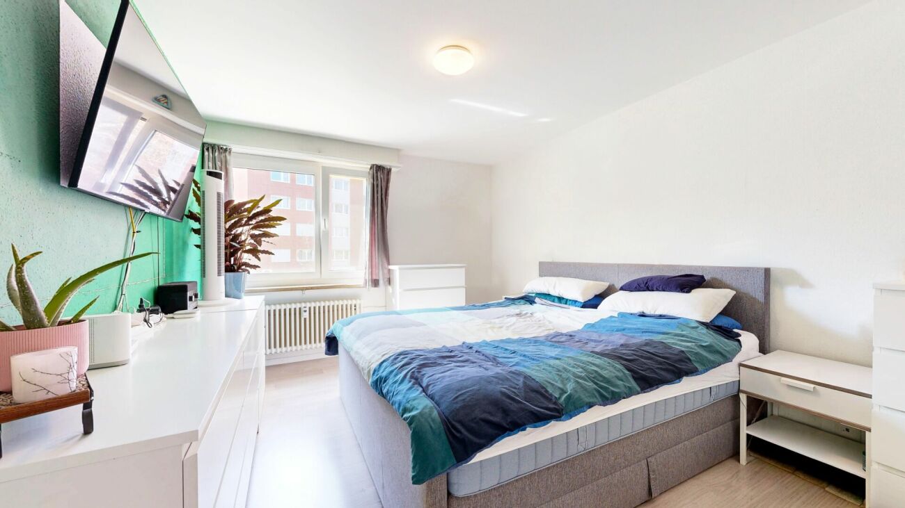Helles Schlafzimmer mit Doppelbett und TV