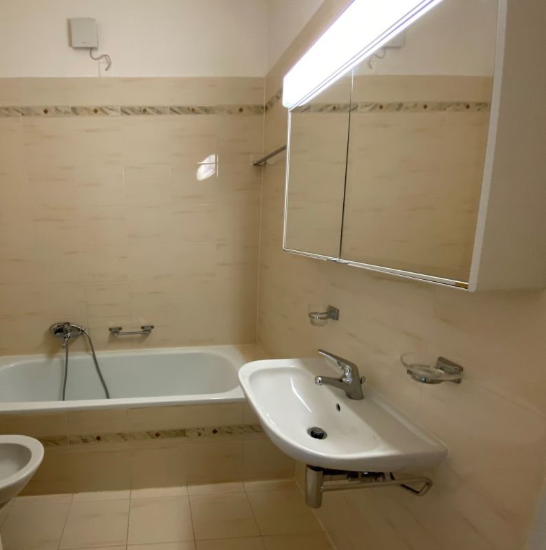 Kleines Badezimmer mit Badewanne und Spiegelschrank
