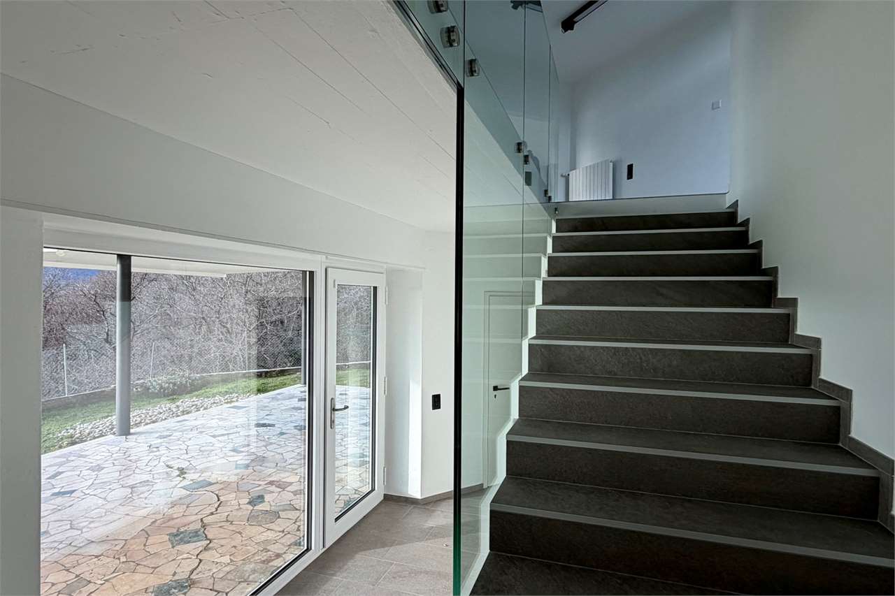 Moderne Treppe mit Glasgeländer und großer Fensterfront