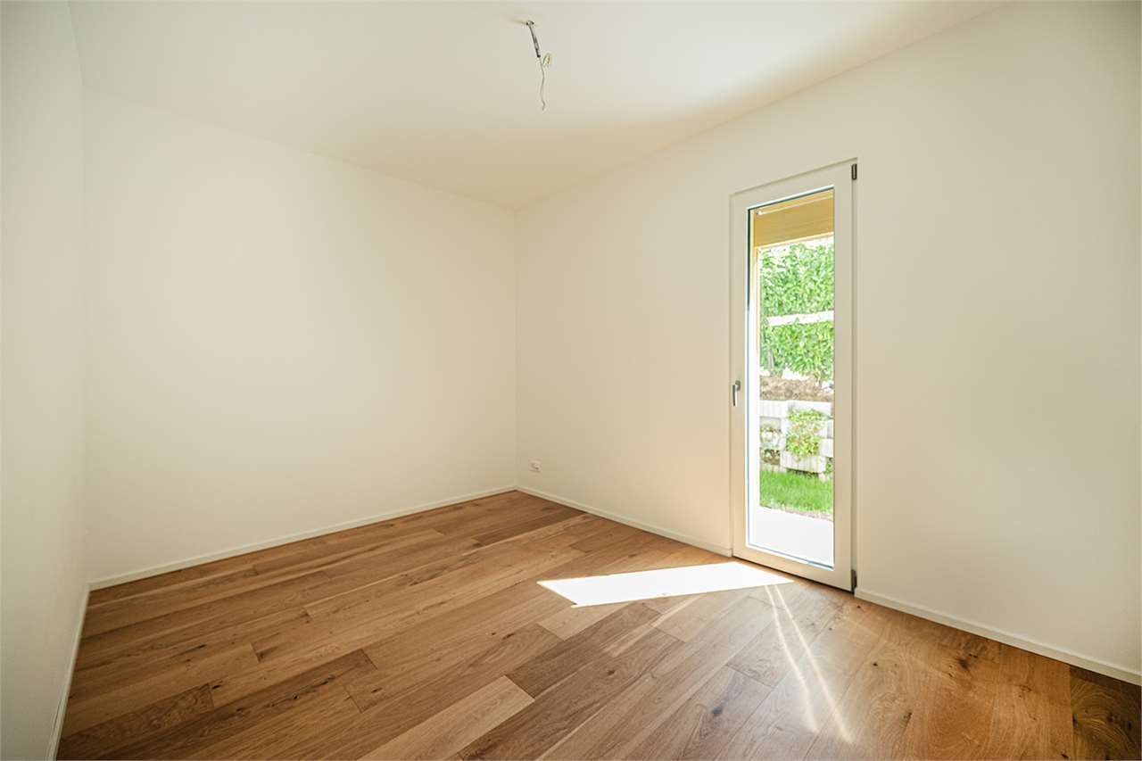 Leerer heller Raum mit Holzboden und Terrassentür