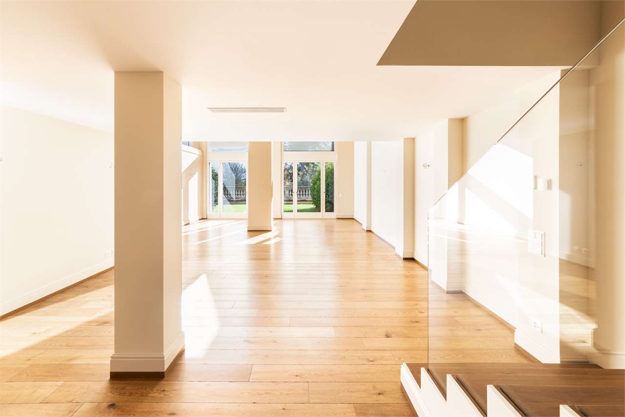 Heller, leerer Wohnraum mit Treppe und Gartenblick