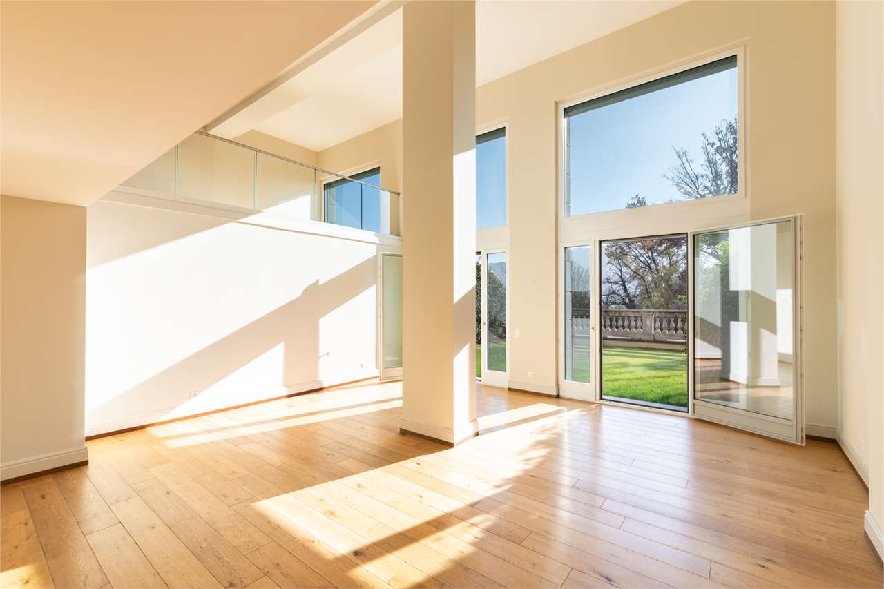 Helles, leeres Loft mit bodentiefen Fenstern und Blick ins Grüne