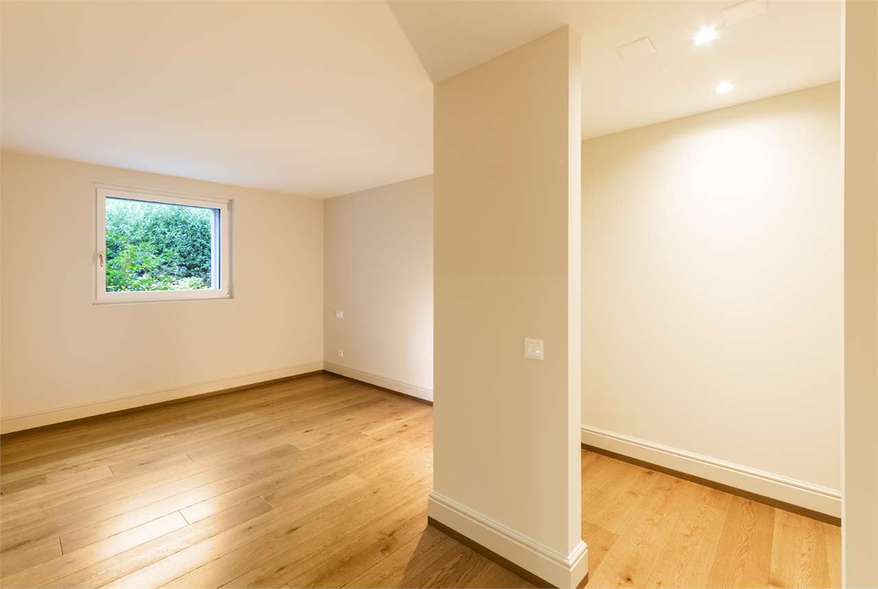 Heller leerer Raum mit Holzfußboden und Fensterblick ins Grüne