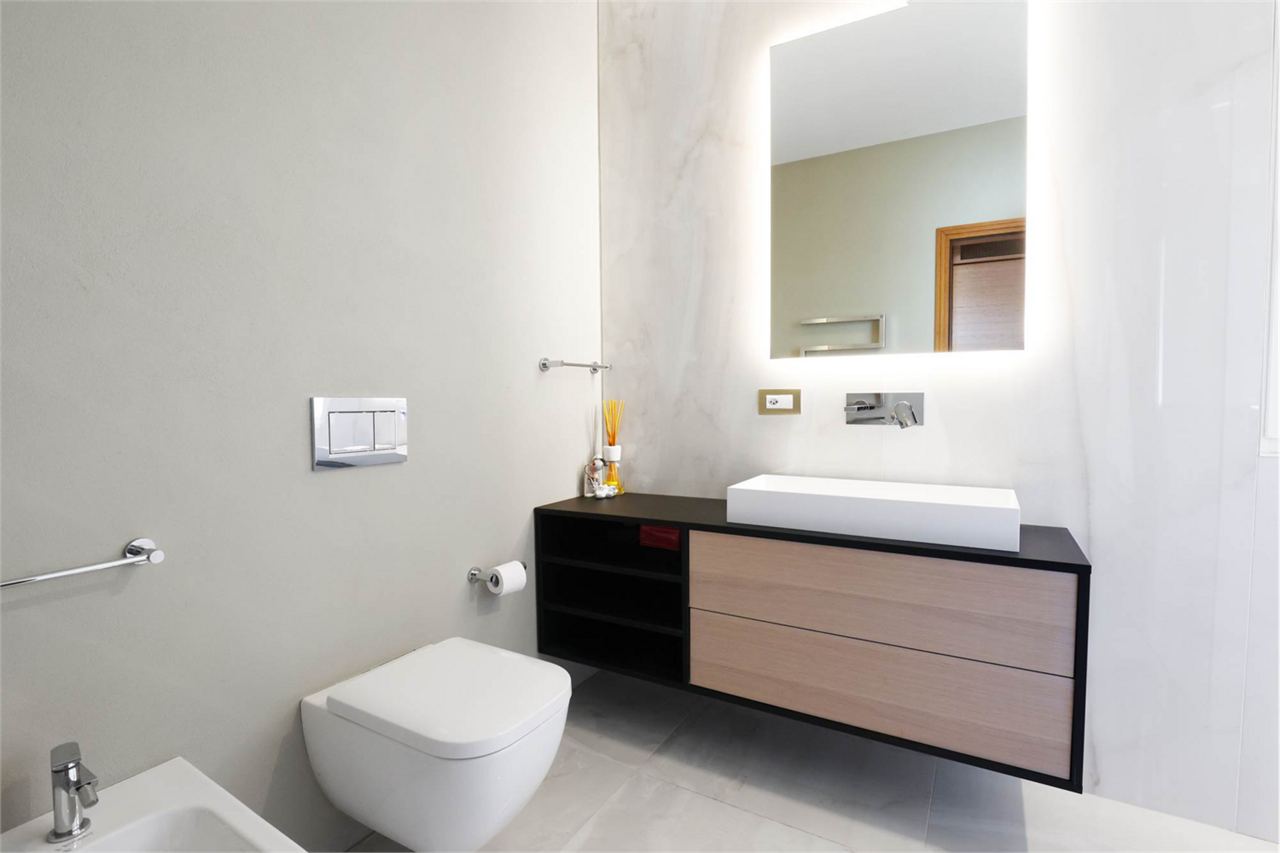 Modernes Badezimmer mit beleuchtetem Spiegel und wandhängendem WC