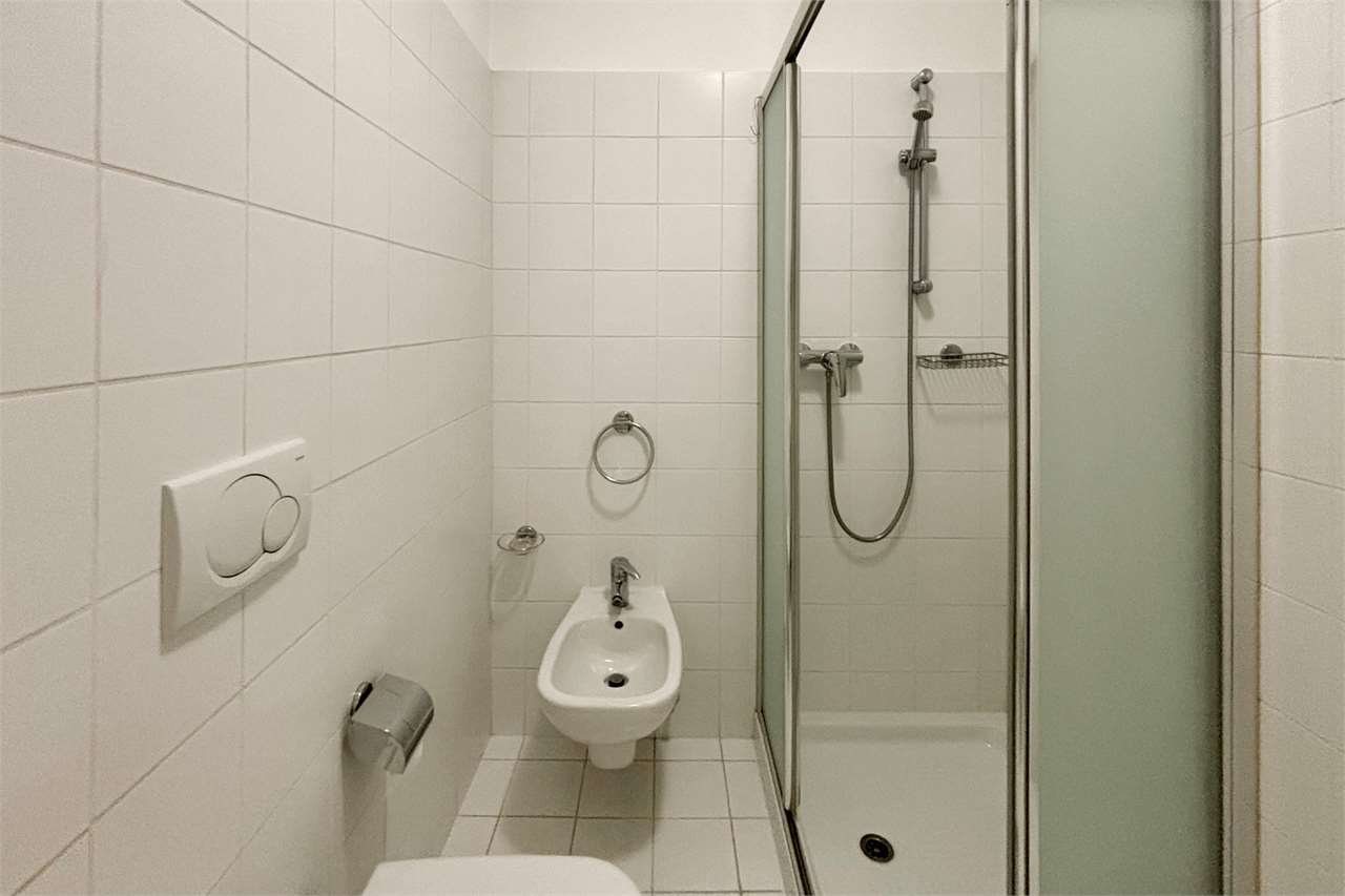 Kleines weiß gefliestes Badezimmer mit Dusche und Bidet