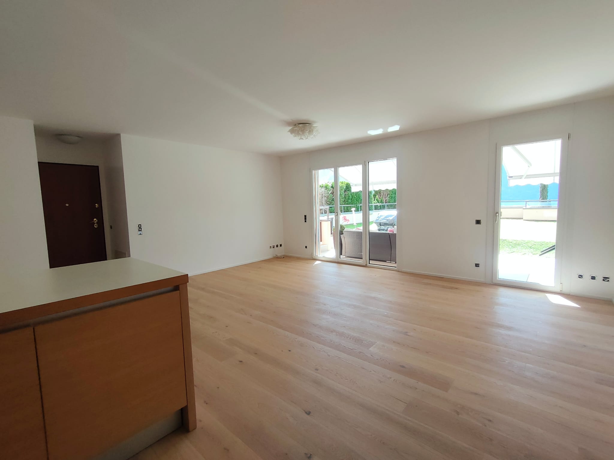Heller leerer Wohnraum mit Holzfußboden und Terrassenblick