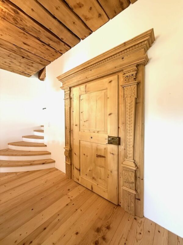 Rustikale Innenansicht mit geschnitzter Holztür und Holztreppe