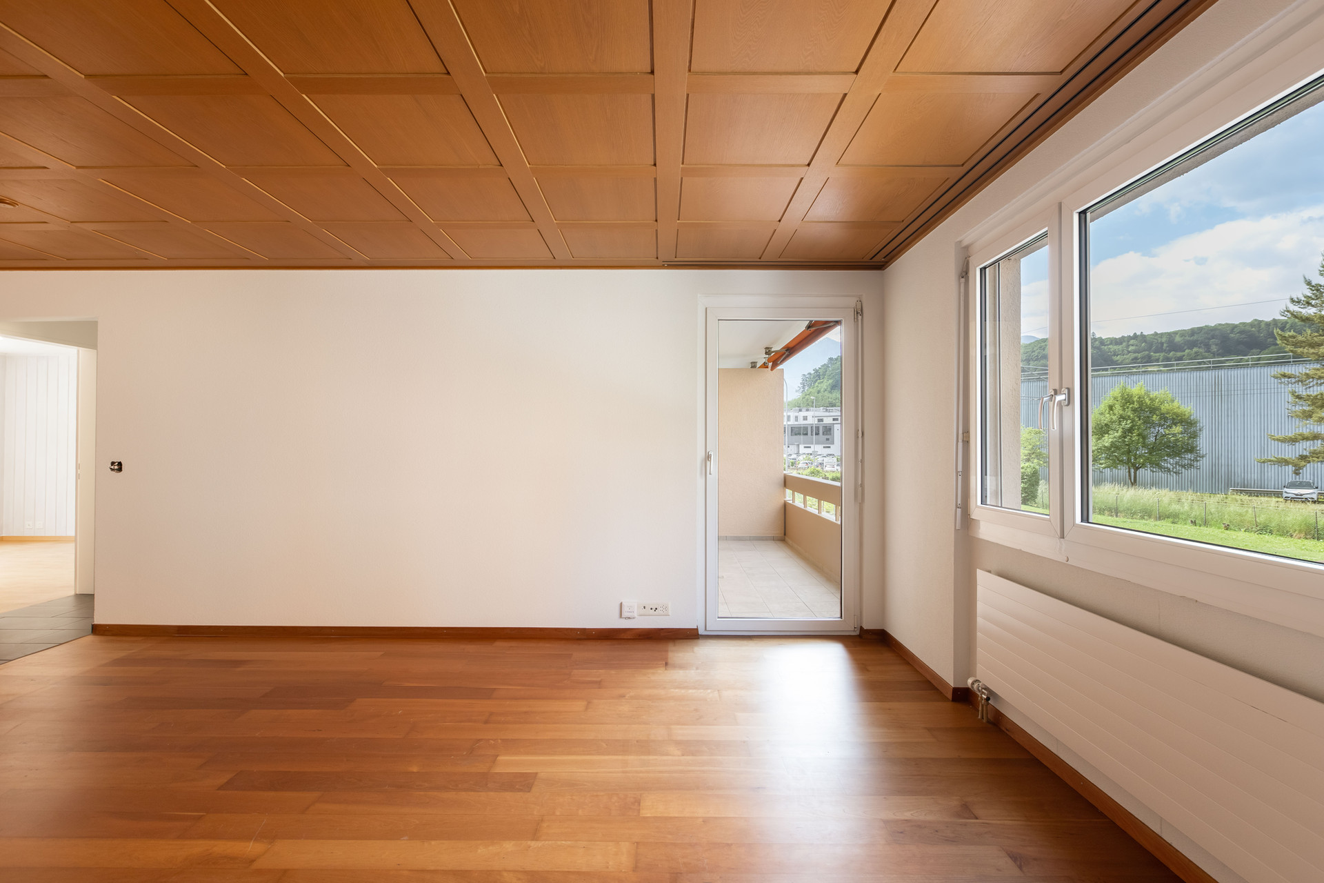 Leerer Wohnraum mit Holzdecke und Blick ins Grüne