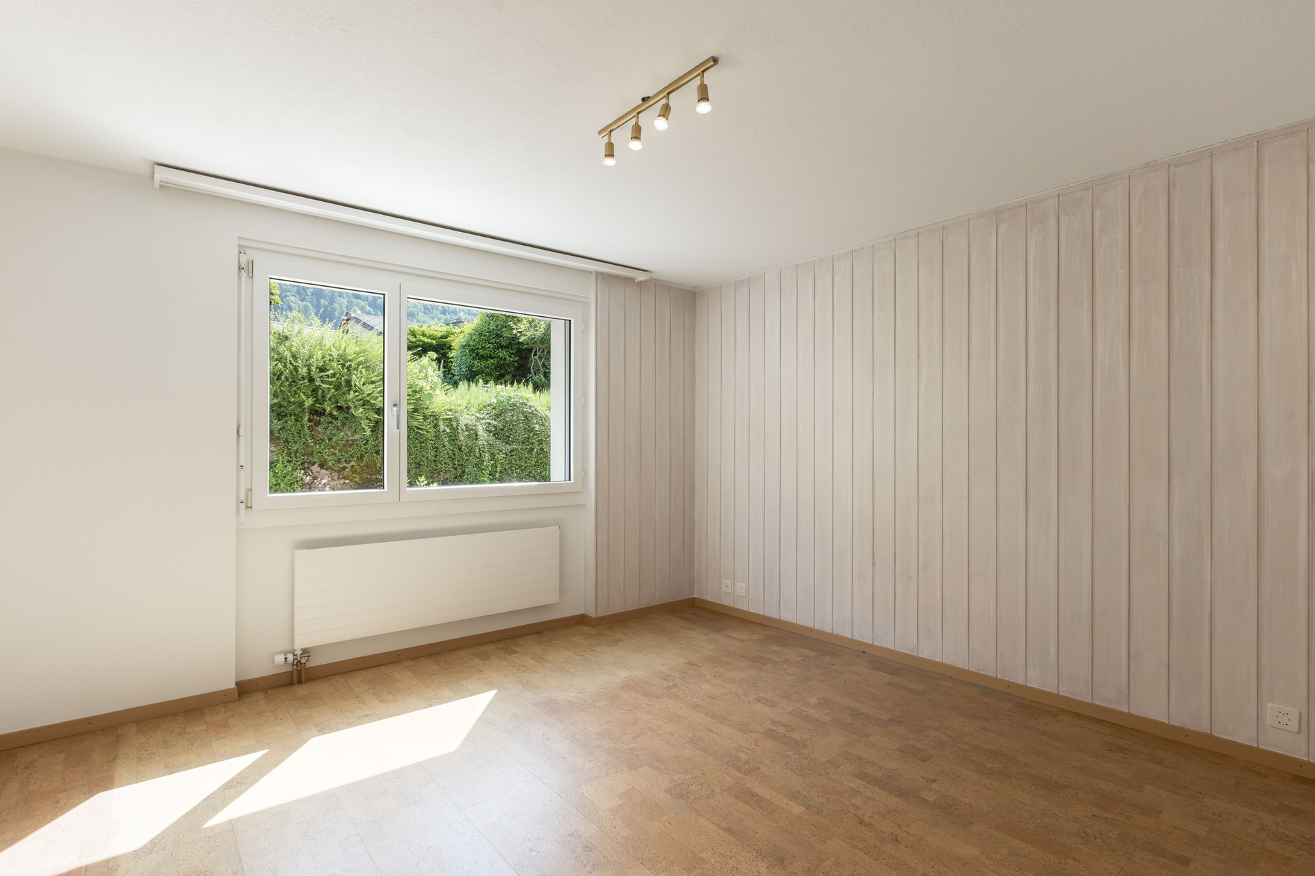 Heller leerer Raum mit Fenster und Holzoptik-Wandverkleidung