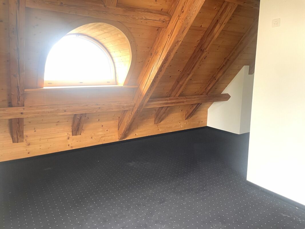 Dachgeschossraum mit Holzdecke und Rundfenster