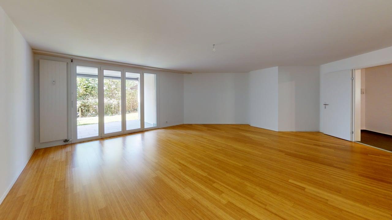 Heller leerer Wohnraum mit Holzboden und Terrassentüren